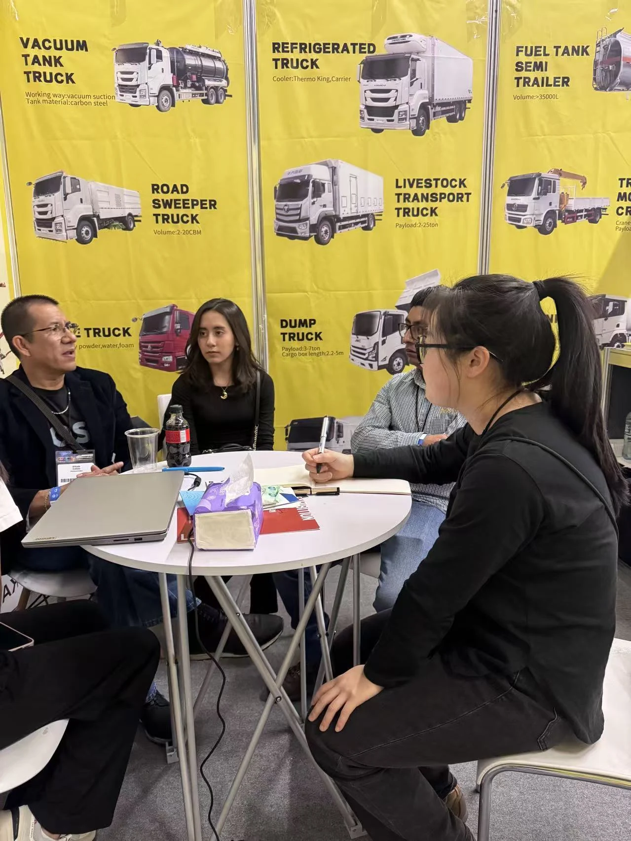 A KEEYAK colleague discussing printed vehicle information with visitors at the Mexico exhibition